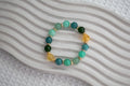 Beaded bracelet with green, blue, and gold crystal beads on a textured white surface