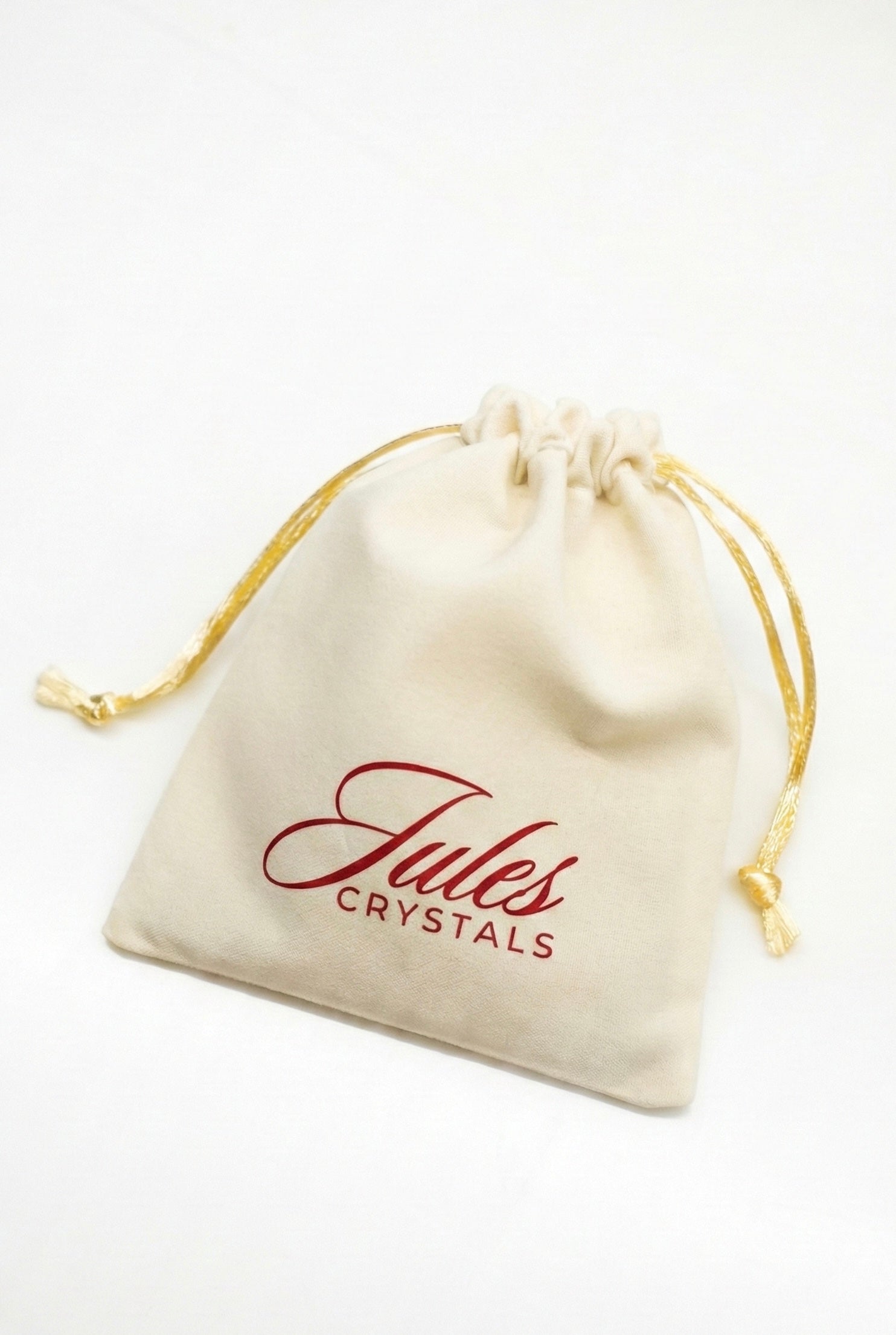 Beige drawstring pouch with 'Jules Crystals' branding on a white background
