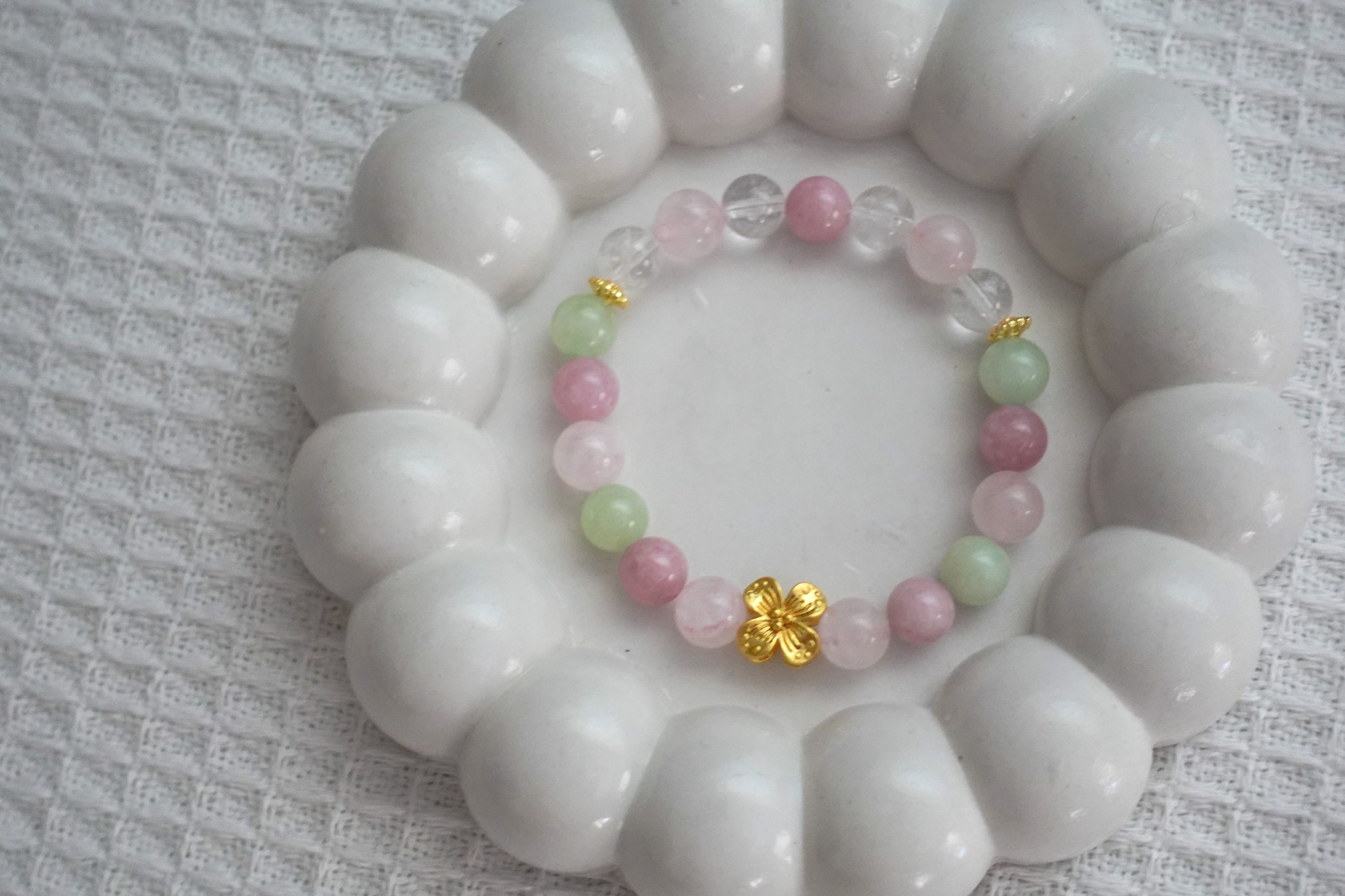 Crystal bracelet with pink, green, and gold beads on a white surface