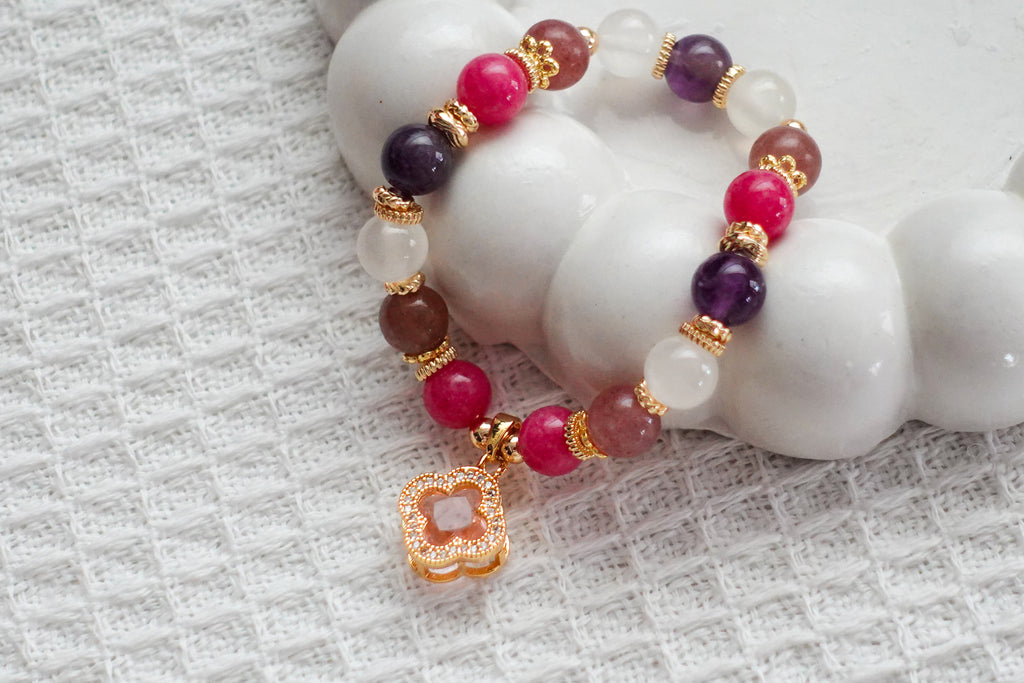 Beaded bracelet with pink, purple, and gold accents on a textured white surface