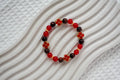 Beaded bracelet with red crystal beads and red 4 four-leaf clover charms on a textured white background