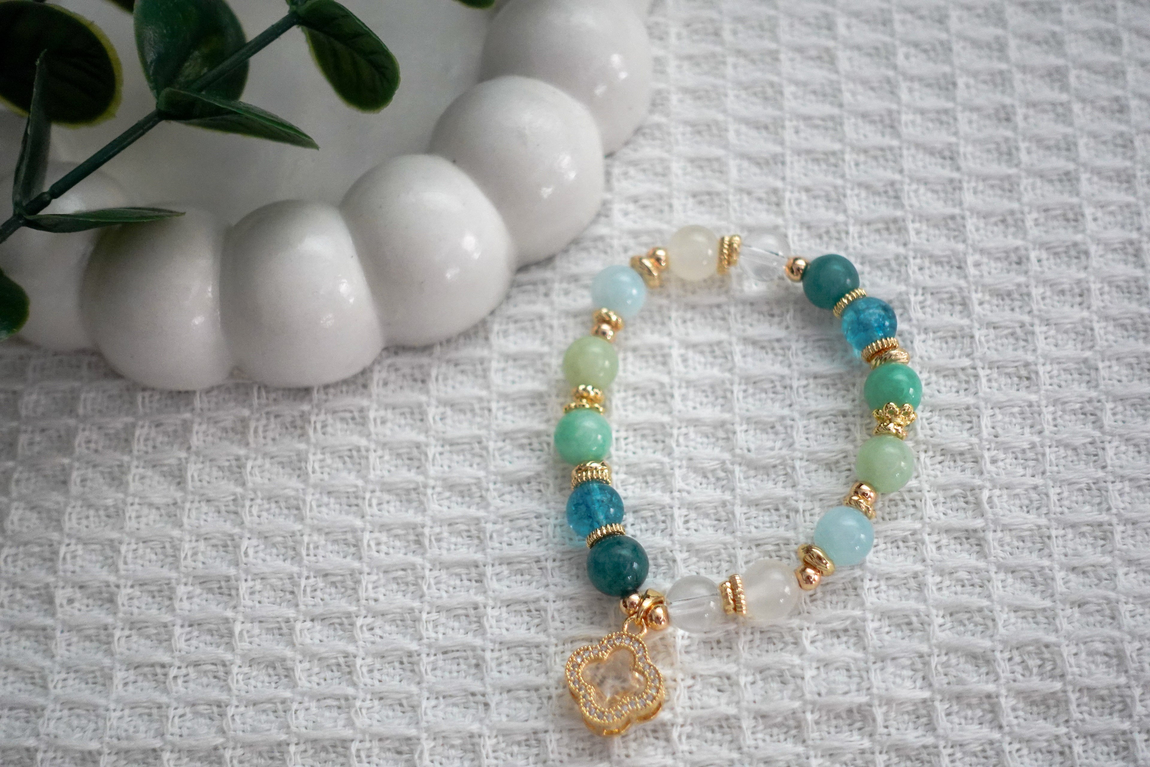 Beaded bracelet with turquoise, gold, and white beads on a textured surface