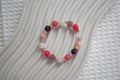 Crystal beaded bracelet with pink, purple, and gold accents on a textured surface
